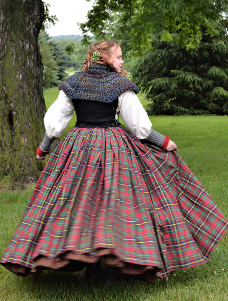 Person wearing a traditional outfit with a plaid skirt in a park setting