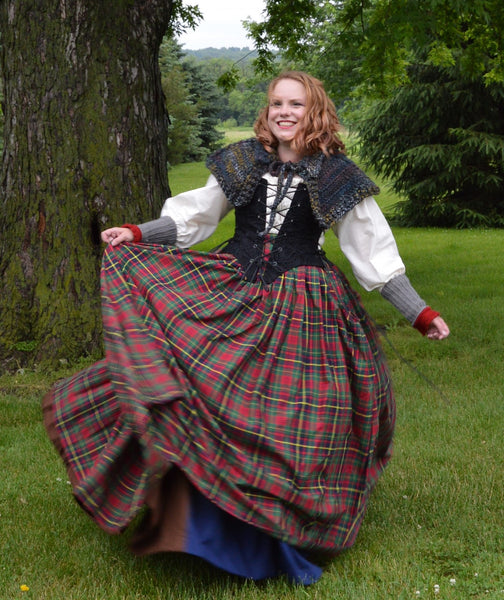 Woman in a traditional Scottish dress standing outdoors with trees and grass in the background